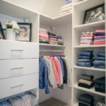 Children's closet full of shoes on shelves and clothing on shelves and hung up on racks