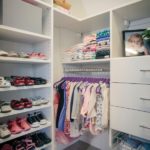 Children's closet full of shoes on shelves and clothing on shelves and hung up on racks